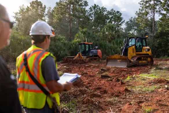 How to choose a land clearing company Jacksonville FL — licensed contractor reviewing permits with property owner before CAT D6N site clearing Duval County